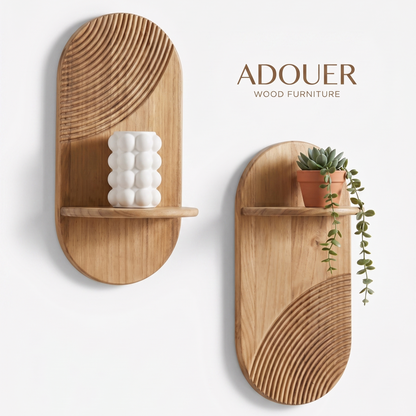 Two oval wooden wall shelves with curved line patterns, shown on a white wall. One shelf holds a white textured vase, and the other holds a small potted succulent.