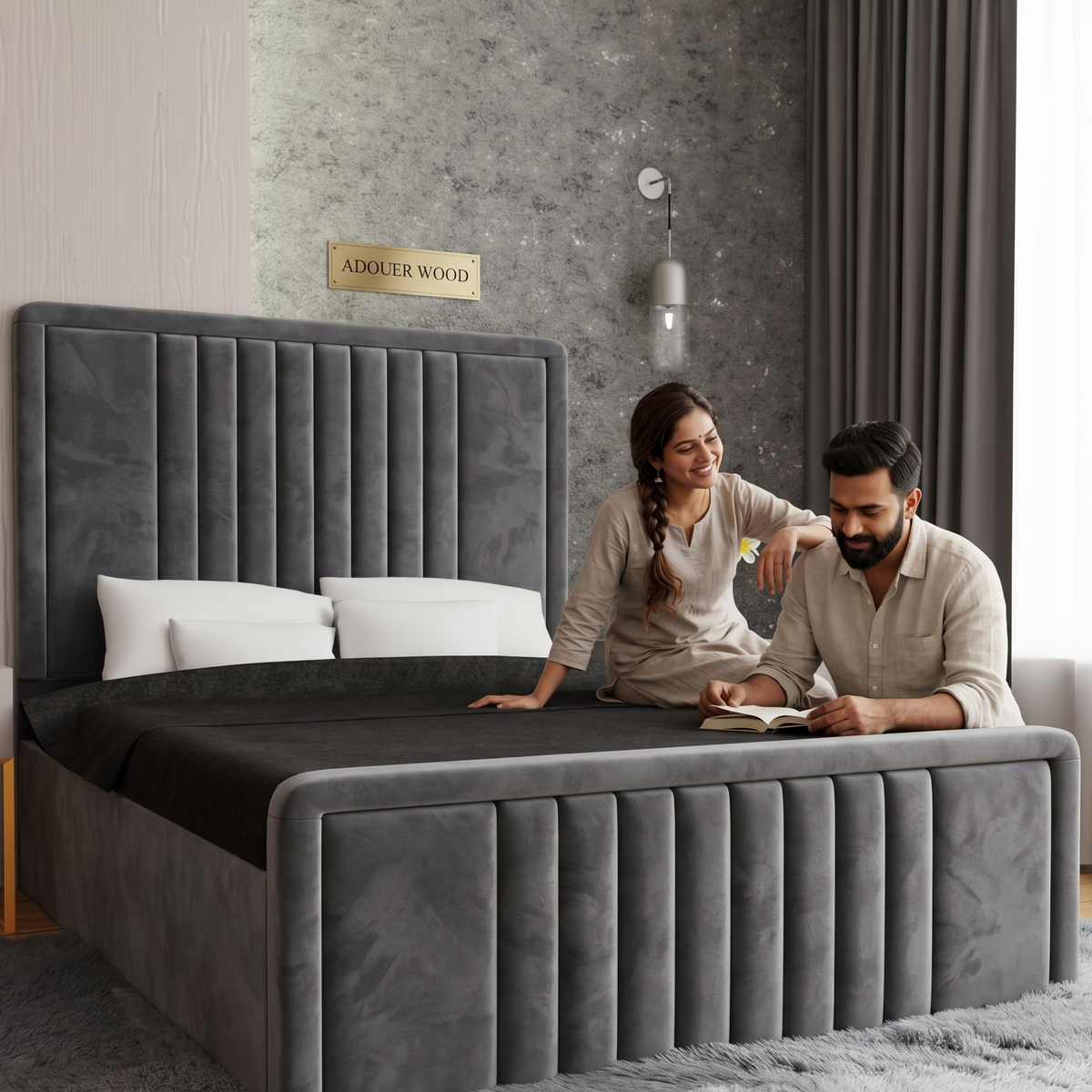 Couple sitting on a gray upholstered bed in a modern bedroom.