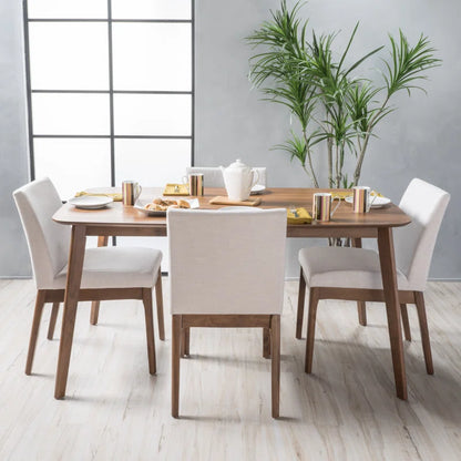 Modern 4-person dining table set with upholstered chairs, featuring a natural finish on acacia wood legs, positioned in a bright room with a plant and minimalist decor.