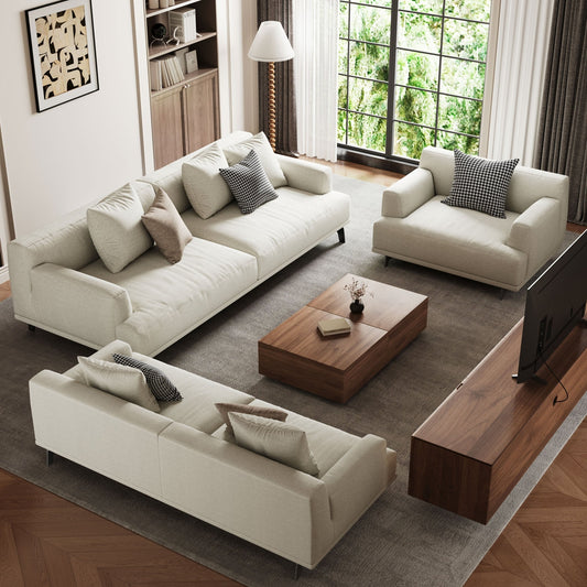 Modern living room with white sofas, a wooden coffee table, and large windows.