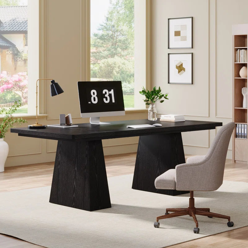 Modern office desk with computer setup in a bright room with large windows.