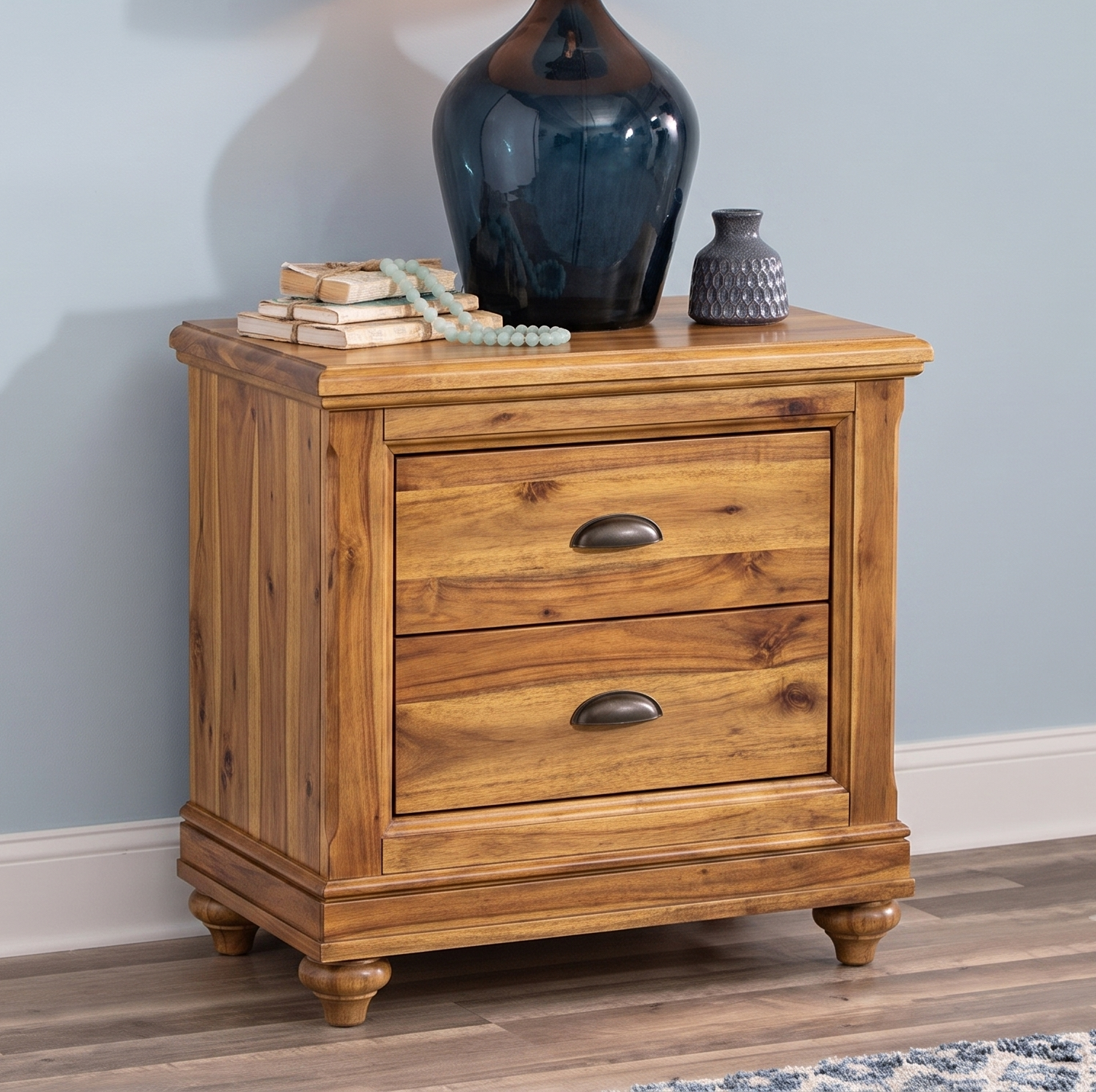 Natural SHEESHAM Wooden nightstand with two drawers against a light blue wall. 