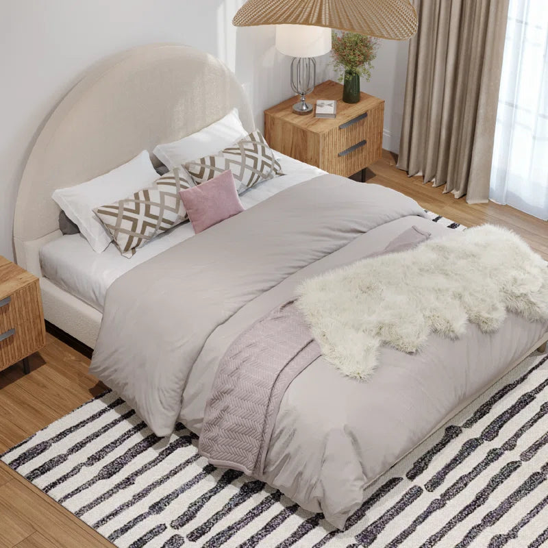Neatly made bed with gray bedding and decorative pillows in a bedroom setting.
