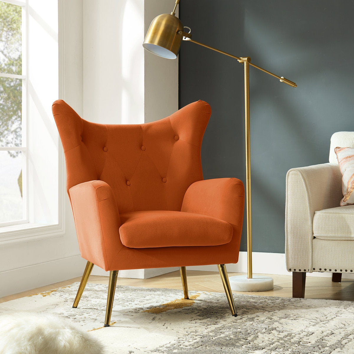 Orange armchair in a living room with a gold floor lamp and beige sofa.