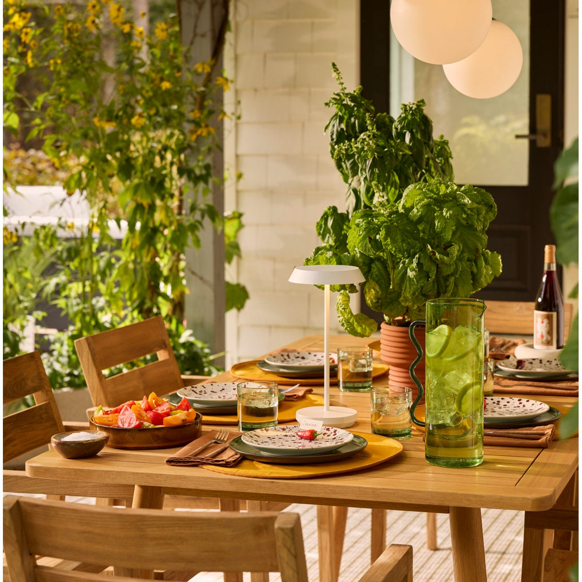 Outdoor dining setup with a wooden table, chairs, and a bottle of wine.