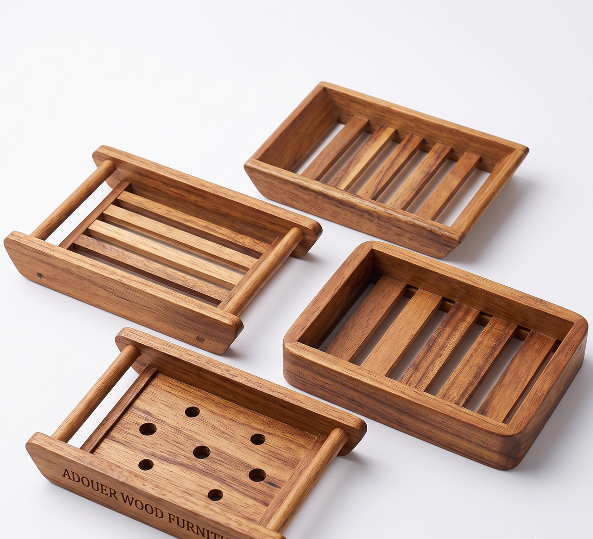 Four rectangular wooden soap dish holders with slatted bottoms, arranged on a clean white background. One dish shows the engraved text 'ADOUER WOOD FURNITURE'.