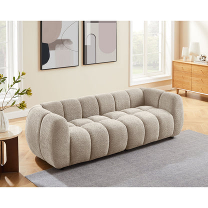 Beige tufted sofa in a living room with abstract art on the wall.