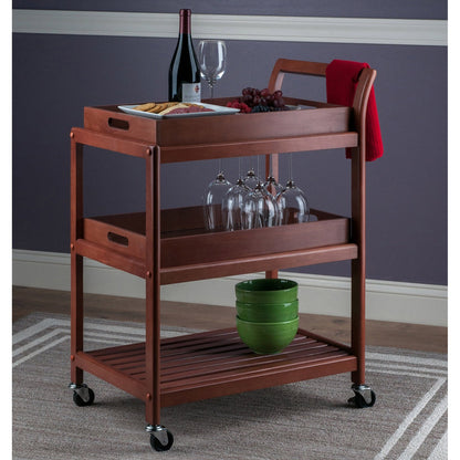 Wooden serving cart with wine bottle, glasses, and food on a gray carpeted floor.