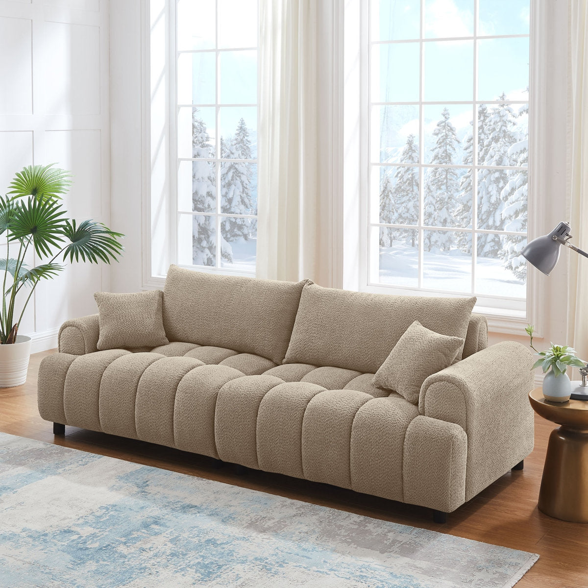 Beige sofa in a bright living room with large windows and decorative plants.