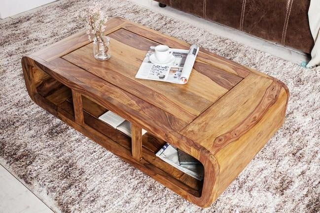 Wooden coffee table with a magazine and small plant on a textured rug
