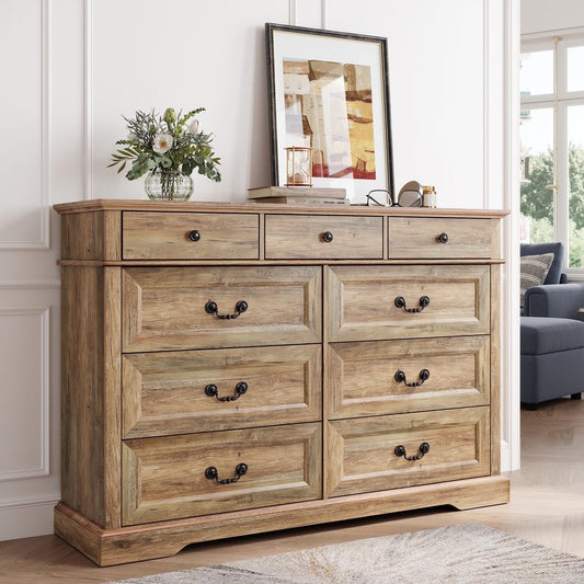 Wooden dresser with decorative items in a room with a couch and window.