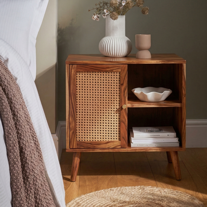 Wooden nightstand with wicker door next to a bed