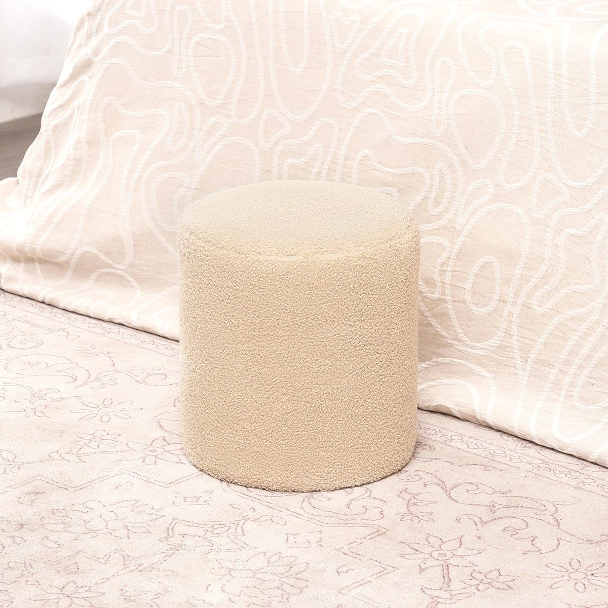 Beige ottoman with a white pillow in the background
