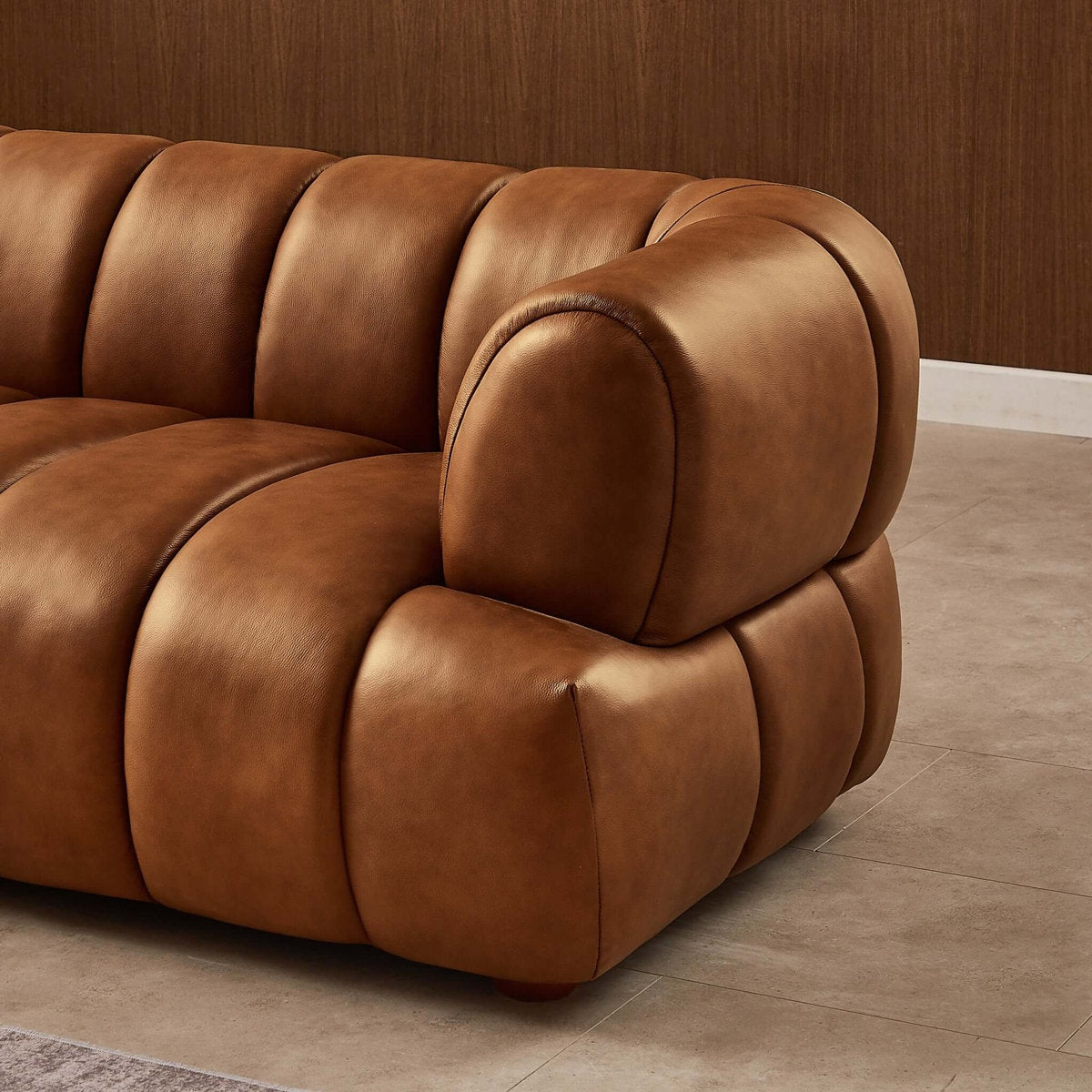 Brown leather sofa against a wooden wall.