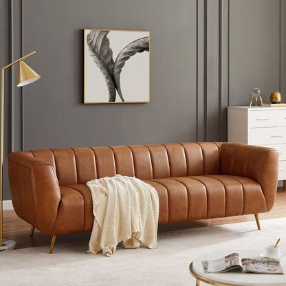 Brown leather sofa in a living room with a lamp, coffee table, and artwork on the wall.