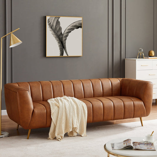 Brown leather sofa in a living room with a lamp, coffee table, and artwork on the wall.