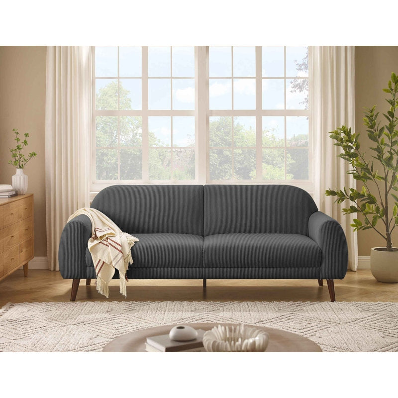 Gray sofa in a living room with large windows and plants