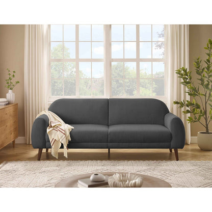 Gray sofa in a living room with large windows and plants