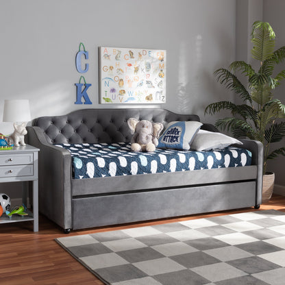 Gray upholstered bed with blue and white patterned bedding in a room with a checkered rug and plants.