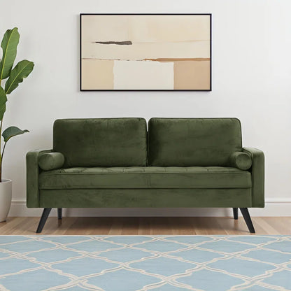 Green sofa in a living room with a abstract painting on the wall and a blue patterned rug.