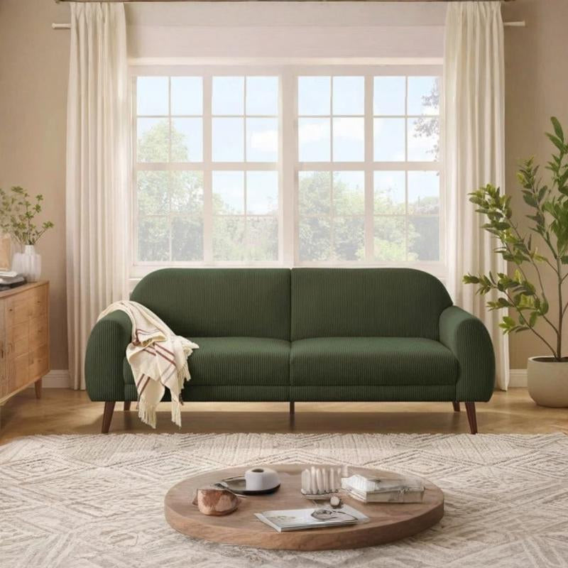 Green sofa in a living room with a wooden coffee table and plants.
