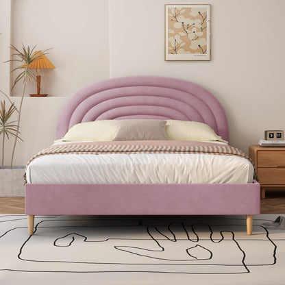 Pink upholstered bed in a bedroom setting with a lamp and artwork on the wall.