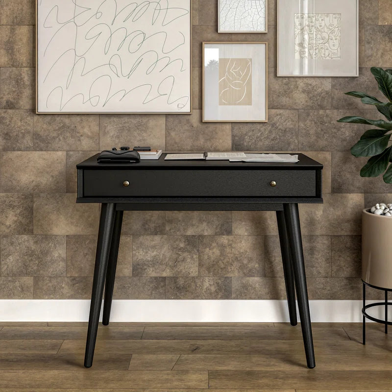 Black desk with a wooden wall and decorative plants in the background