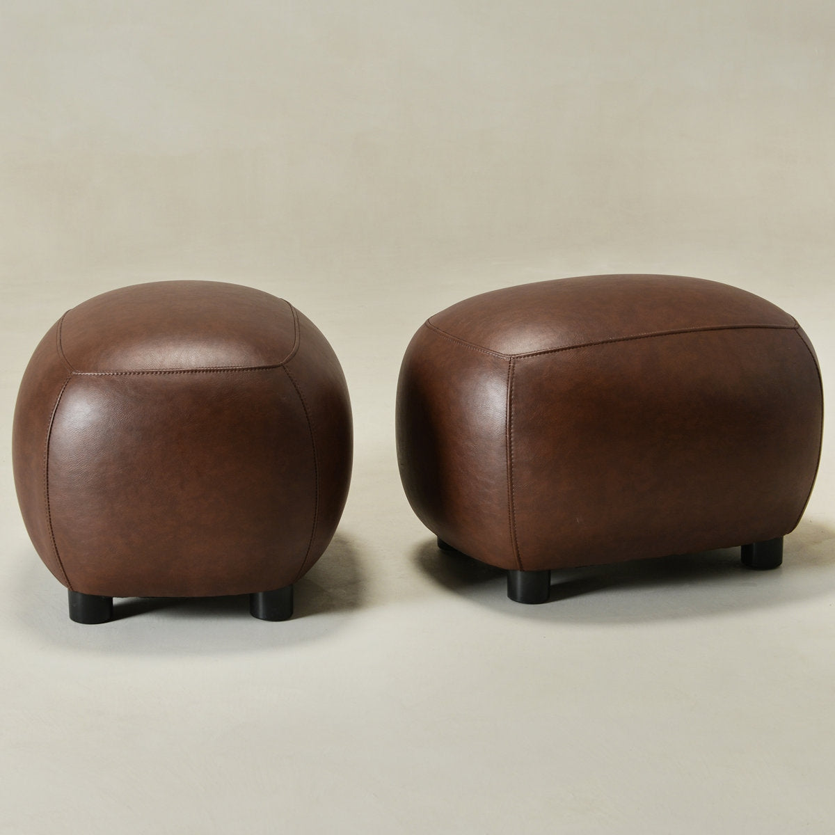 Two brown leather ottomans on a beige background