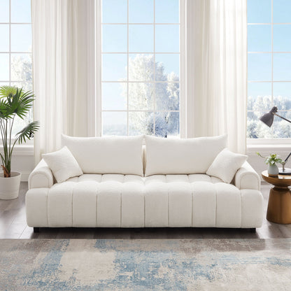 White sofa in a bright living room with large windows and a plant.