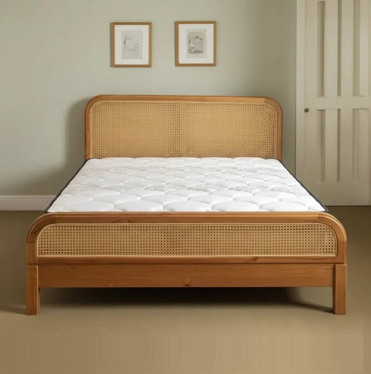 Wooden bed frame with wicker headboard and footboard in a room setting.