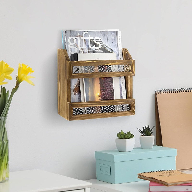 Wooden wall-mounted magazine rack with books and a vase of flowers on a white surface.