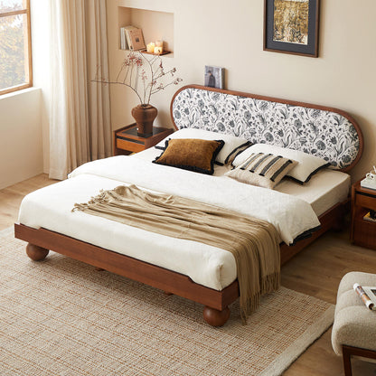 Bedroom with a wooden bed featuring a floral headboard, white bedding, and decorative pillows.