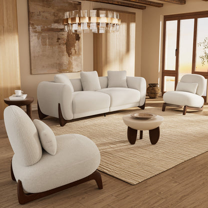 Modern living room with white sofa and armchairs, wooden coffee table, and decorative elements.