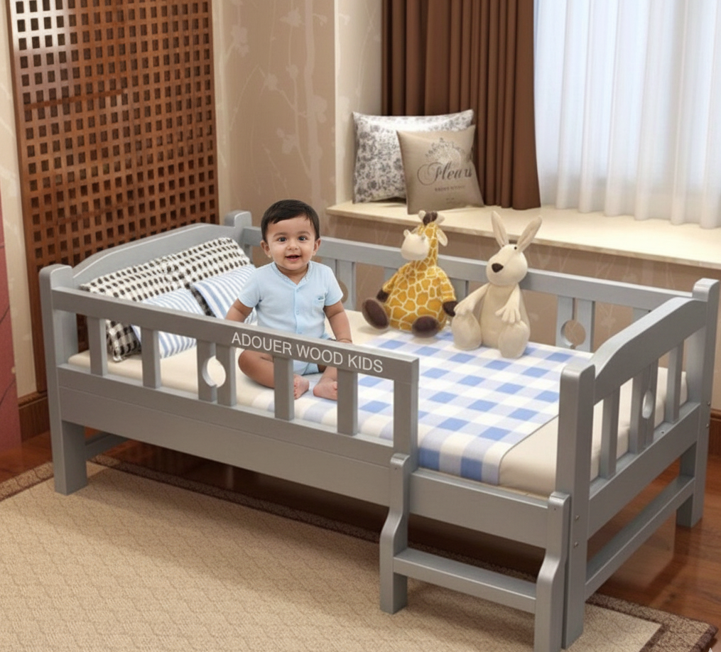 Child sitting on a gray children's bed with stuffed animals in a room.