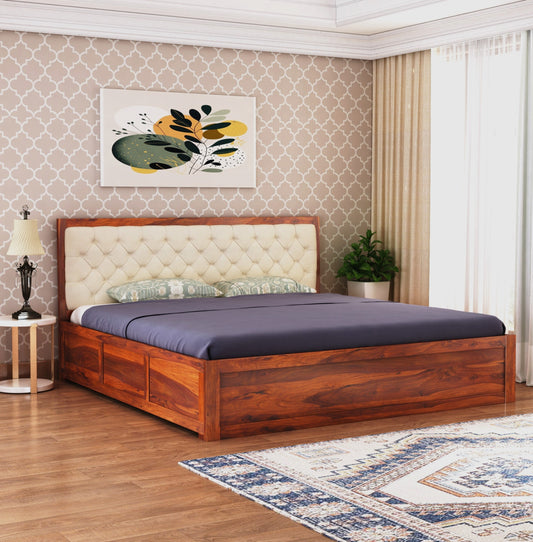 Sheesham wood bed with beige upholstered headboard and box storage, in a room with patterned wallpaper and a painting above the bed.