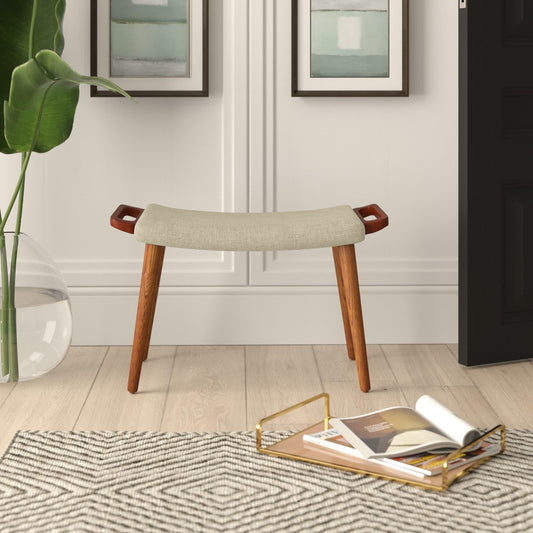 Small stool with wooden legs and a fabric seat in a room with a rug, tray, and plant.