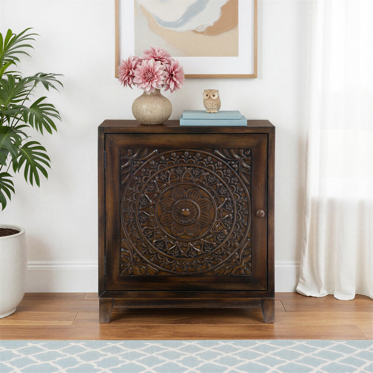Wooden cabinet with decorative carvings in a room with a plant and artwork on the wall.