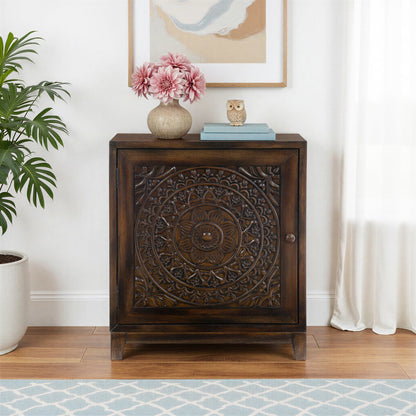 Wooden cabinet with decorative carvings in a room with a plant and artwork on the wall.