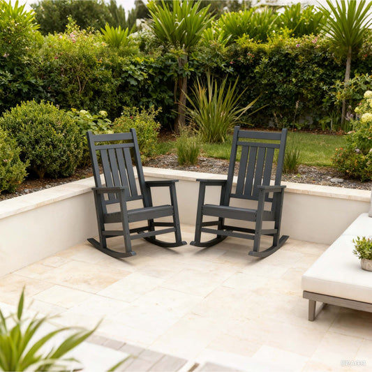 Two gray rocking chairs on a patio with greenery in the background