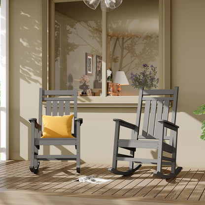 Two gray rocking chairs on a wooden deck with a yellow pillow and a small table in the background.
