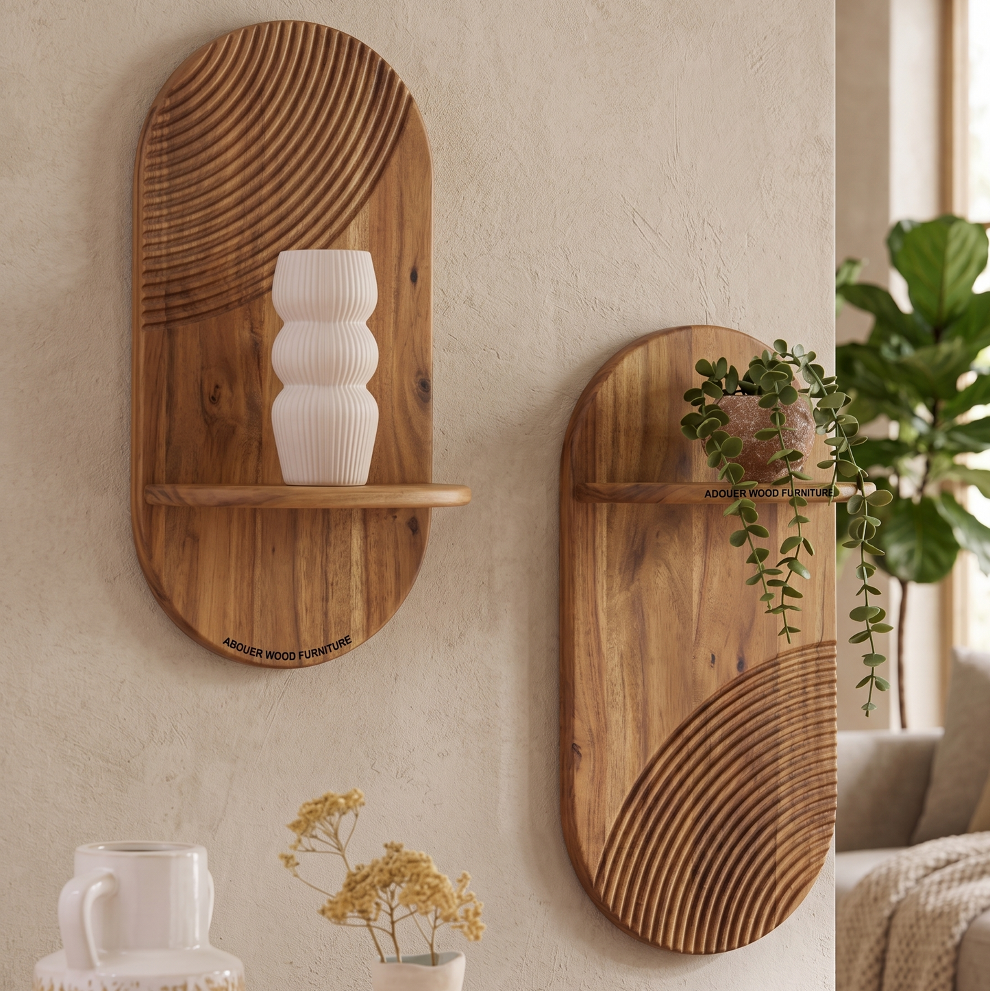 Two oval wooden wall-mounted shelves with carved linear patterns, displayed on a textured beige wall in a styled interior setting. One shelf holds a white ribbed vase, and the other has a trailing green plant.