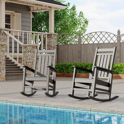 Two rocking chairs on a wooden deck by a pool with a house and garden in the background.