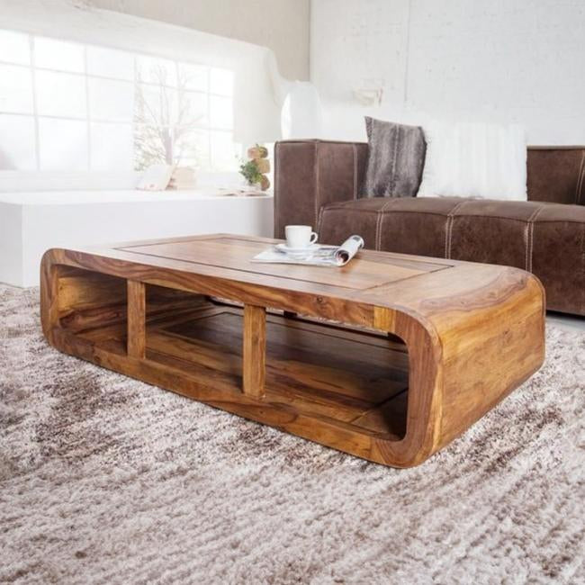 Wooden coffee table in a living room with a brown sofa and white walls.