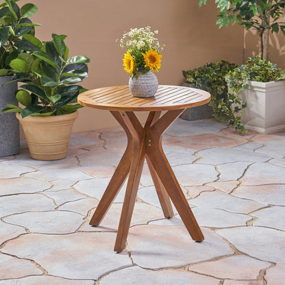 Wooden side table with a vase of flowers on a stone patio