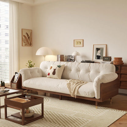 A beige upholstered cotton fabric sofa with wooden legs placed in a well-decorated living room setting.