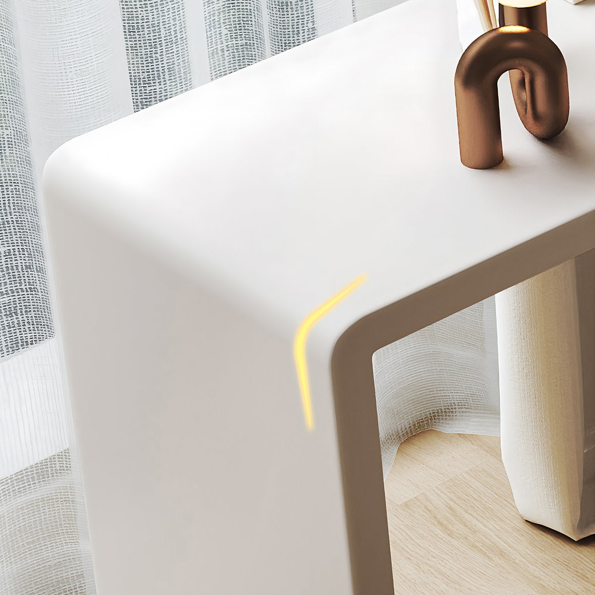 White table with a gold vase and a yellow straw on a light wooden floor.