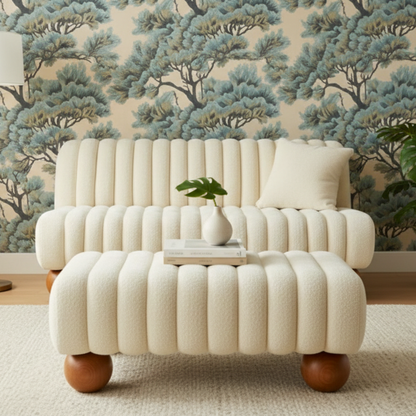 White textured sofa with wooden legs in a room with tree-patterned wallpaper.