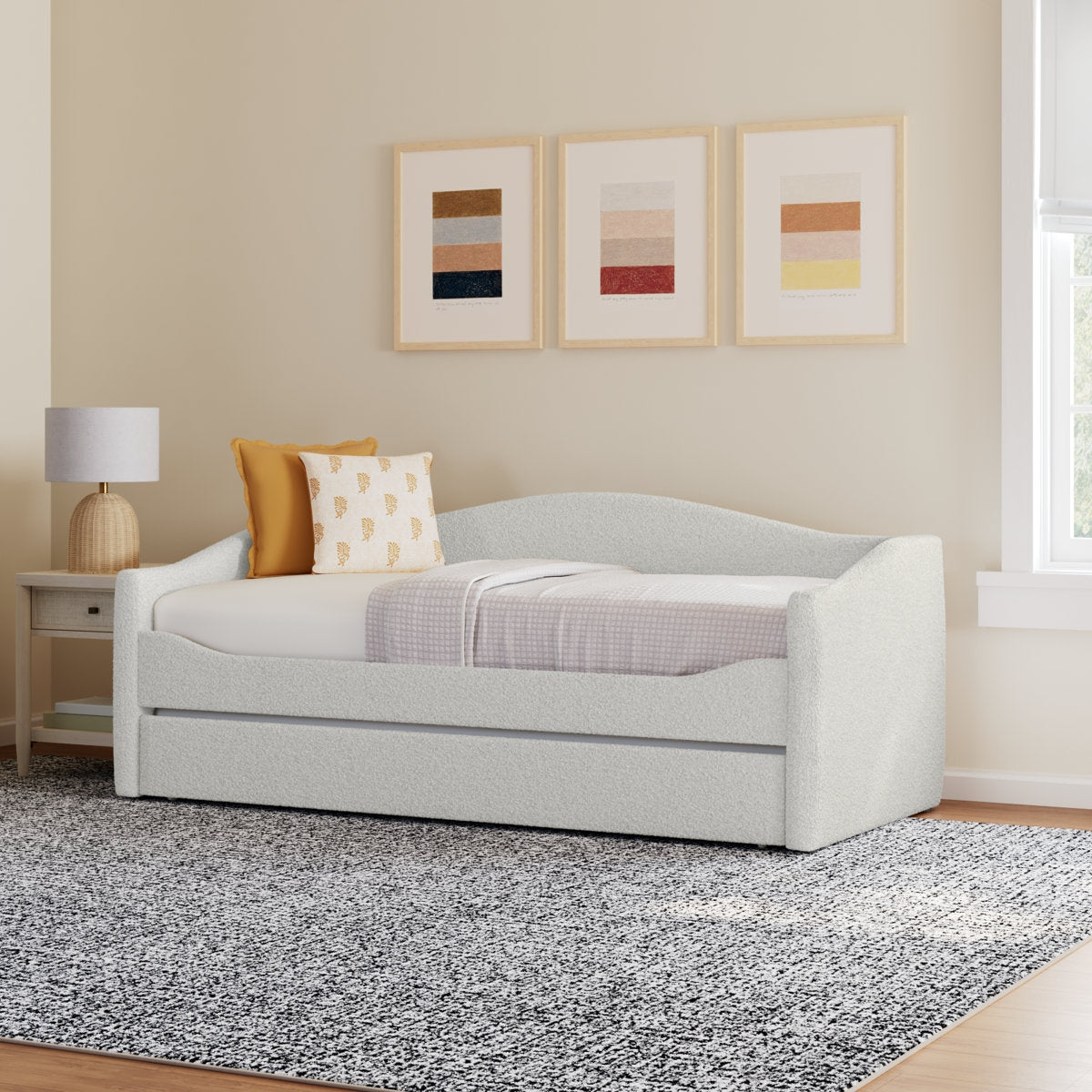White upholstered bed with bedding in a room with framed art on the wall.