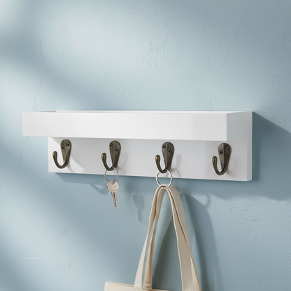 White wall-mounted rack with four hooks holding a bag and keys against a light blue wall.