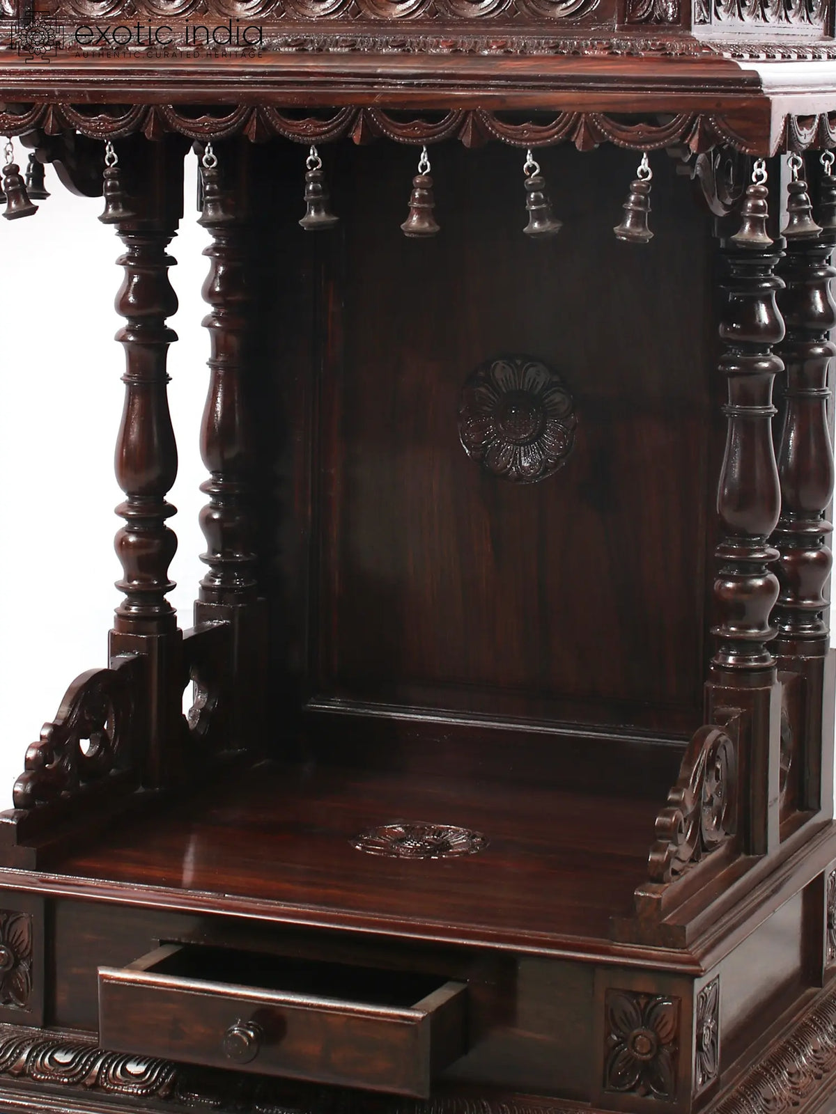 Wooden altar with intricate carvings and hanging bells on a white background